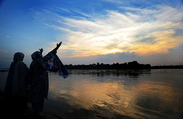 Pakistani women pray at sunset by the Ravi river in Lahore on August 2, 2010. (Arif Ali/AFP/Getty Images) 
