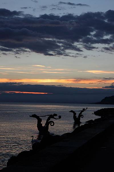 河邊的雕刻似乎正開心地舞動著，為這夕陽嘉年華畫下完美的句點