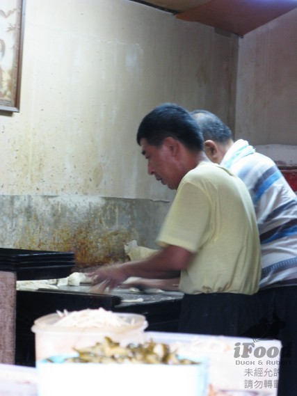 06_屋裡一旁二男人正在邊桿皮邊烤燒餅.jpg