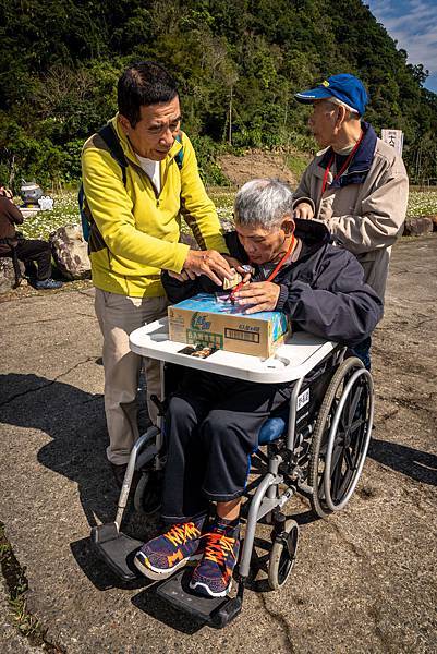 （圖說：用餐時，李木根細心協助住民們喝水、開點心袋子。）