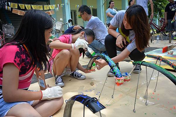 逆風少年指導小朋友彩繪自已單車上的擋泥板
