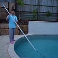 小漁工打掃泳池，要用超長的桿子掃池底