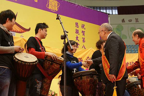 主席蕭義明在喜樂保育院R.J.P.打擊樂團表演後，用力握住每一位服務對象的手心