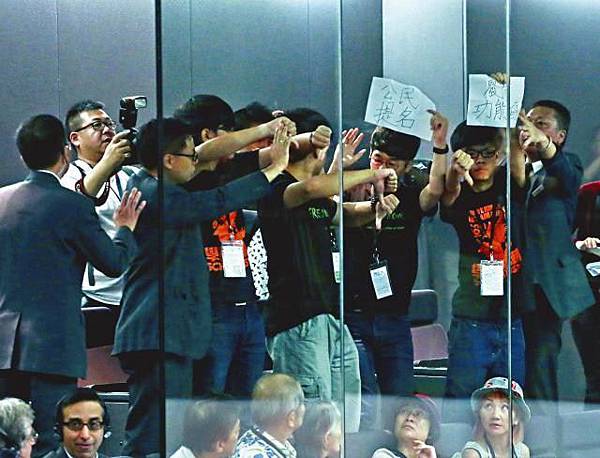 ■學民思潮成員在立法會公眾席倒豎拇指及舉標語，表達對政改諮詢報告的不滿。