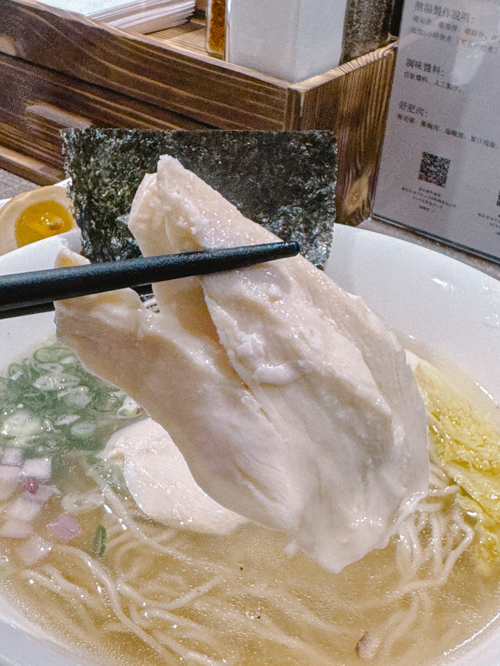 招牌清澈拉麵特寫，湯頭濃郁有雞骨香，配料包含紫洋蔥與青蔥
