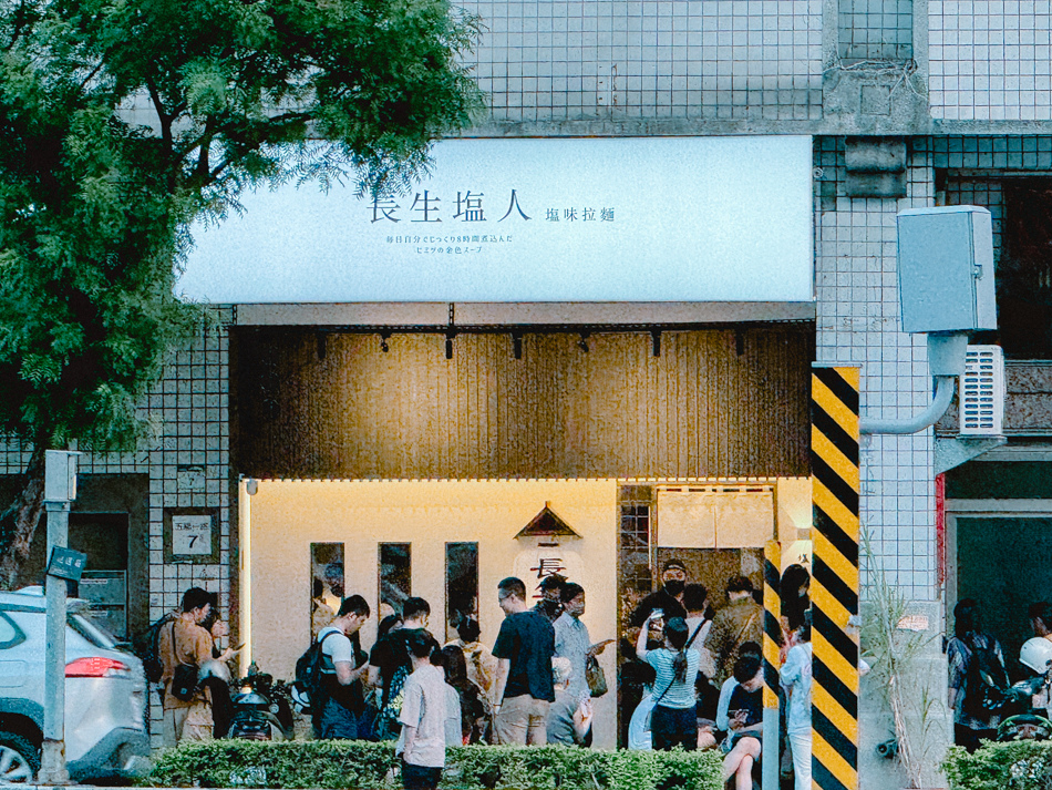 店外候位區及對街高樓景觀，顯示等候客人與周邊市區氛圍
