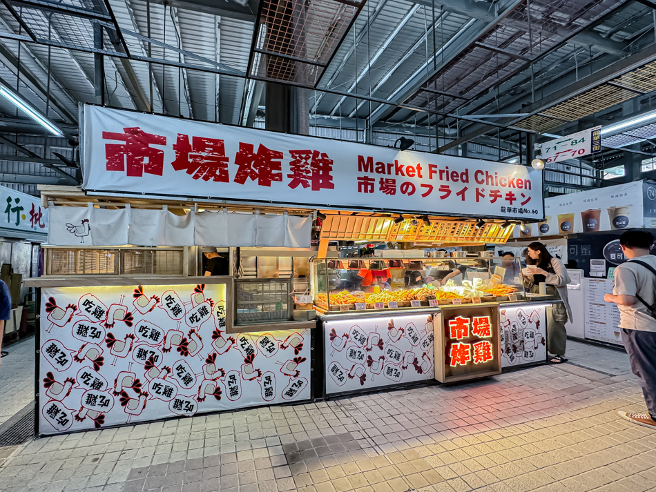 市場炸雞攤位招牌展示，紅字與日文標示吸引顧客