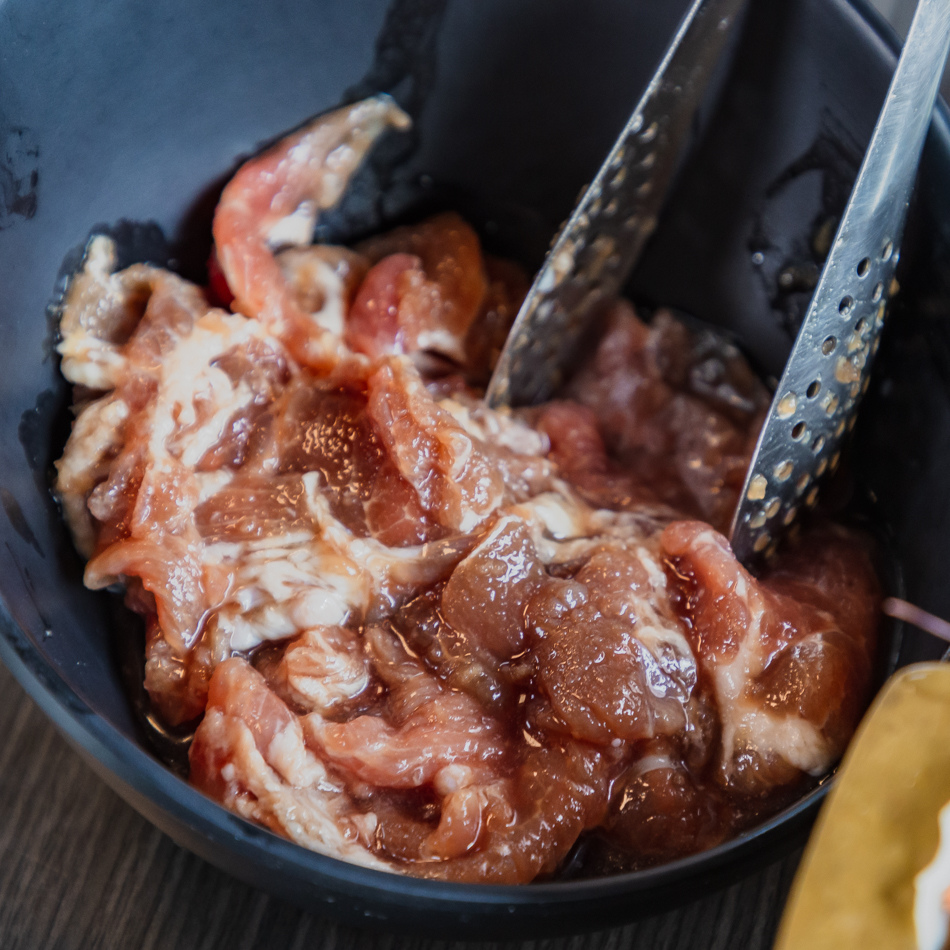 銅盤烤肉肉片煎烤中，油花四溢