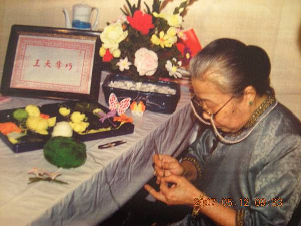 Mrs. Ho Lyan Yu Wen, the creator of Everlasting Blossoms. This picture shows that she was crocheting something at her working table. The red rose in the bonsai was the very first flower she crocheted for her sw