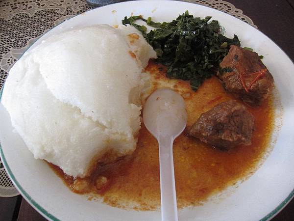 ugali食用成品（白色塊狀物），搭配羊肉塊與芥菜，約新台幣50元。