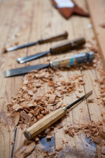 Several wood chisels on a wooden work bench with wood shavings around___.jfif