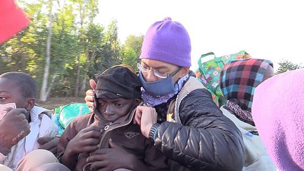 在馬拉威搭車時一路寒冷，謝睿哲幫一名馬拉威小孩拉起外套