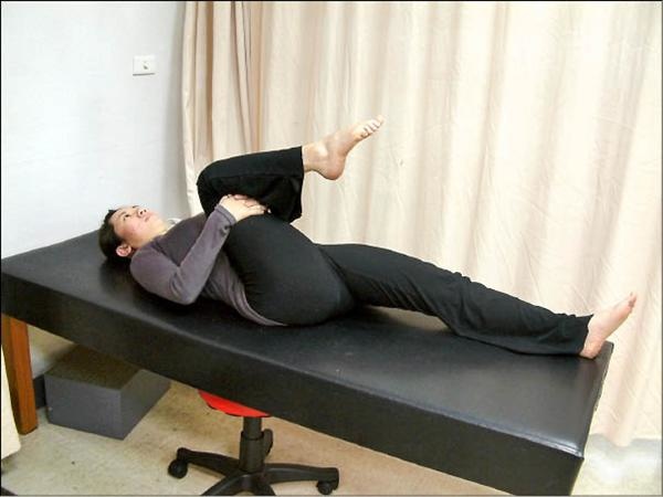 臀大肌復健運動01-正躺於床上，患側單腳儘量靠近胸部做拉筋運動