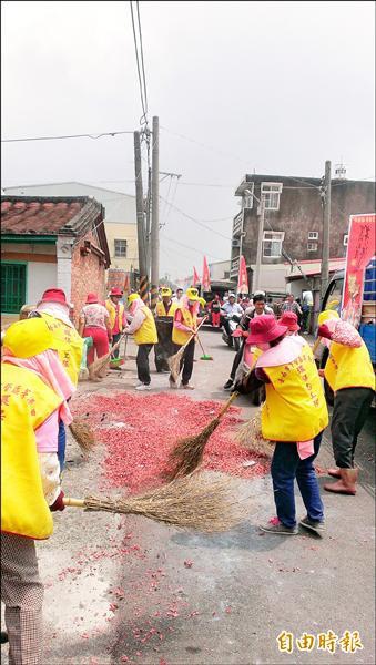 茅港里環保志工跟在遶境隊伍後面，迅速清掃滿地的鞭炮屑，恢復街道清潔。