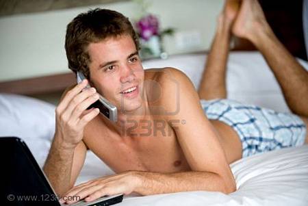 2705841-a-young-man-using-computer-and-phone-whilst-lying-on-bed.jpg