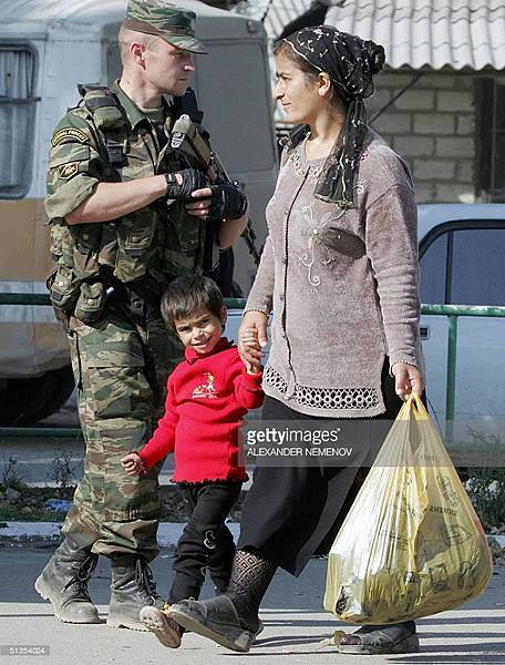 24th September, 2004. A local Chechen woman and her child are overwatched by an MVD Spetsnaz trooper during the human rights conference nearby..jpg