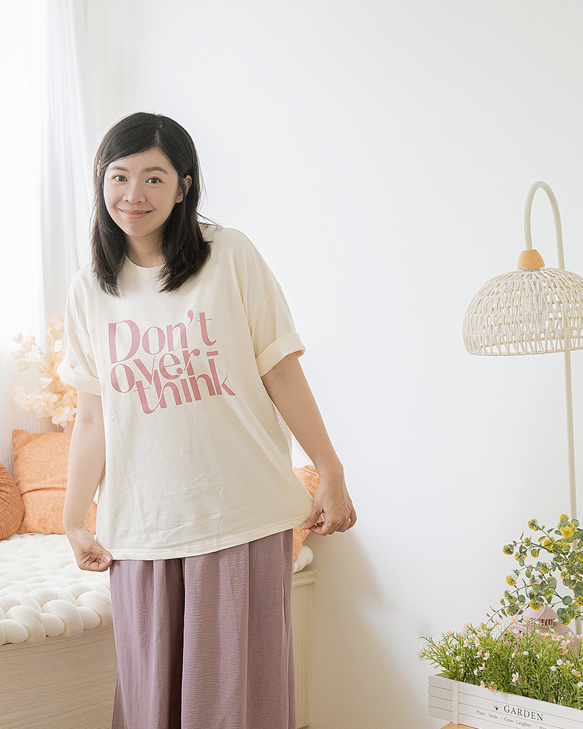 棉花糖女孩坐在床邊，穿著白色字母T恤與薰衣草紫長裙，背景為柔和色調的居家空間，展現OB design夏季穿搭的甜美風格與日系感氛圍