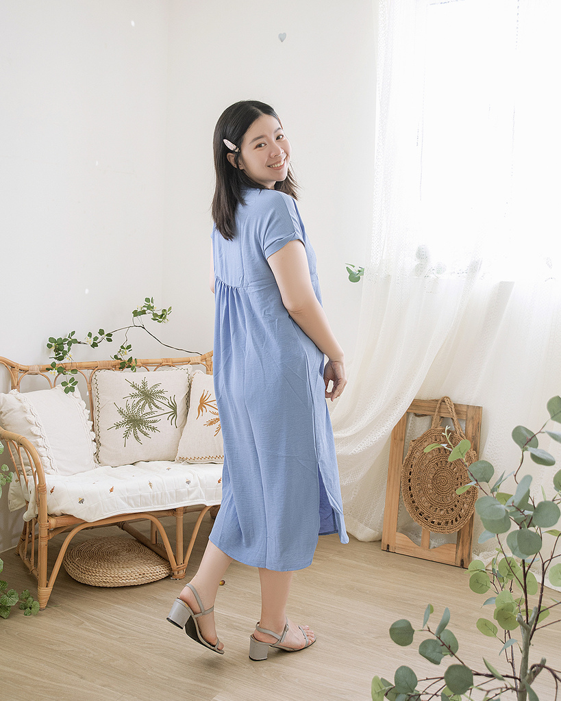 大尺碼女孩雙手輕握蝴蝶結領口，身穿淡藍色短袖洋裝，展現背後抓皺與圓弧下擺設計，適合夏季穿搭與約會造型