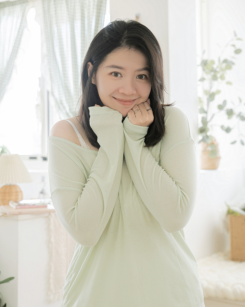 大尺碼女孩穿著薄荷綠長袖針織上衣，袖口微蓋手部，站在柔光灑落的房間中，展現OB設計的舒適材質與夏季穿搭的療癒氛圍