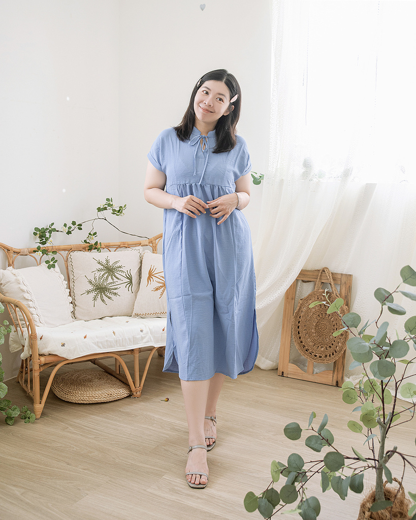 棉花糖女孩穿著淡藍色蝴蝶結洋裝，搭配涼鞋站在自然光充足的房間中，展現2025夏季穿搭的甜美風格與日系度假感